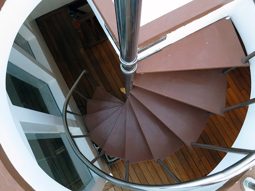 Top-down view of modern brown spiral staircase with metal railing