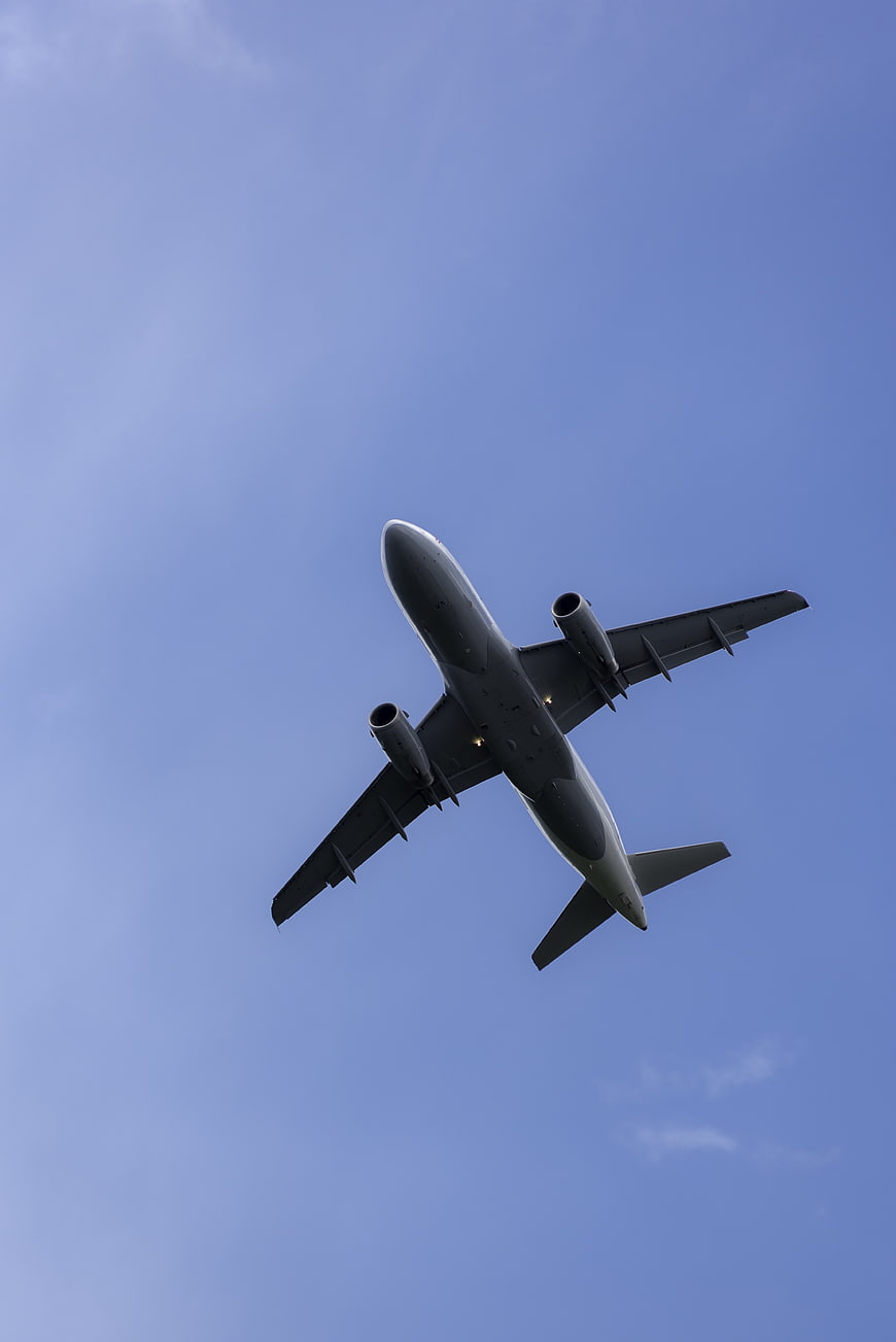 Commercial Airplane Flying Overhead Against Blue Sky