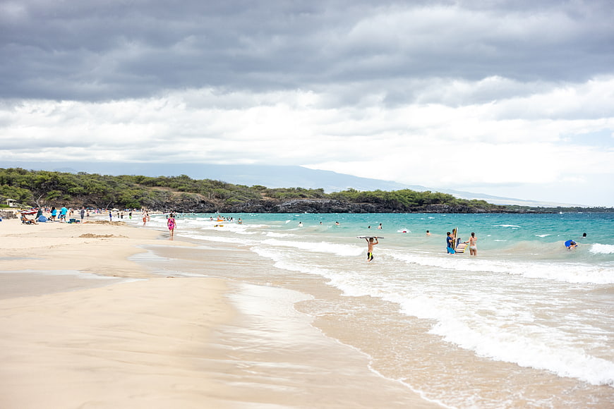 Wide Beach Scene with Surfers and Cloudy Sky