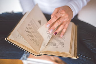 Close-up of woman turning pages of old book