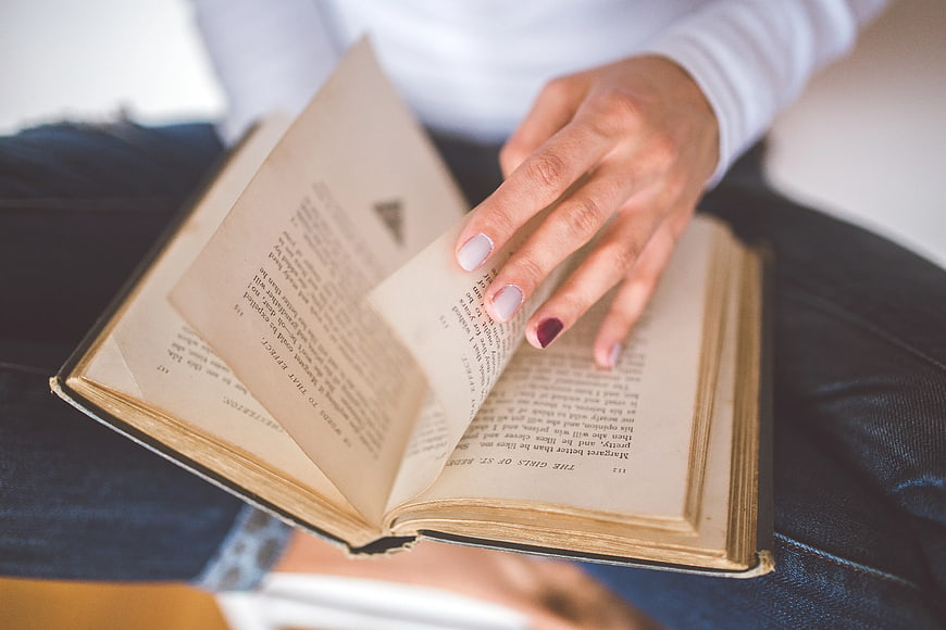 Close-up of woman turning pages of old book