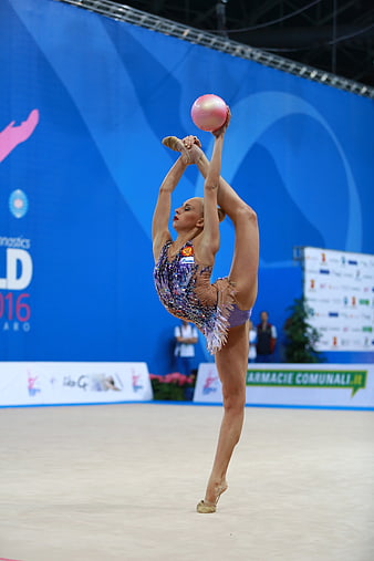Rhythmic gymnast performing standing split with ball
