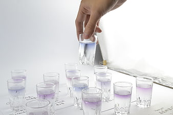 Hand holding test tube with purple liquid over lab samples