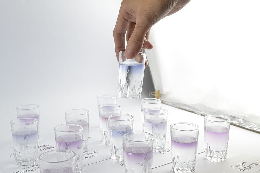 Hand holding test tube with purple liquid over lab samples
