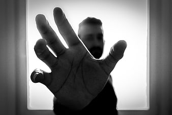 Dramatic black and white silhouette of man reaching hand forward