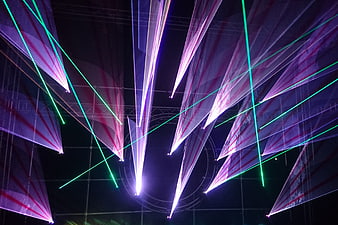 Abstract purple and green laser light beams on dark background