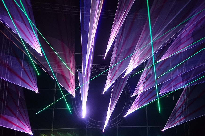 Abstract purple and green laser light beams on dark background