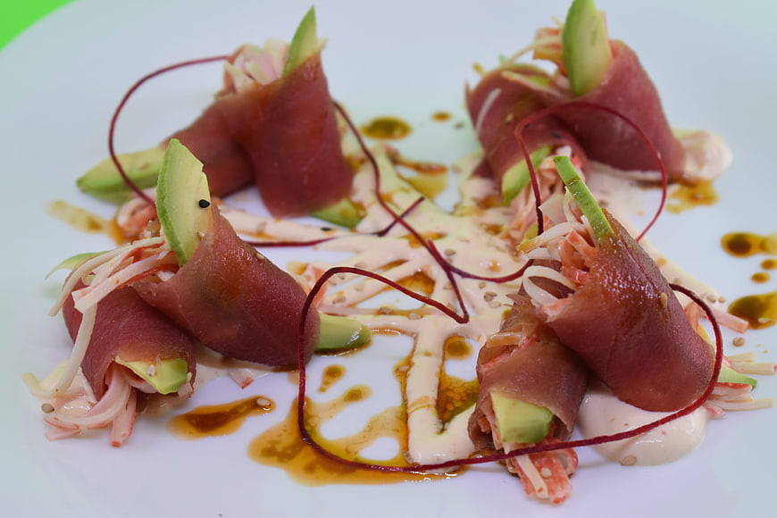 Gourmet prosciutto and avocado rolls on white plate