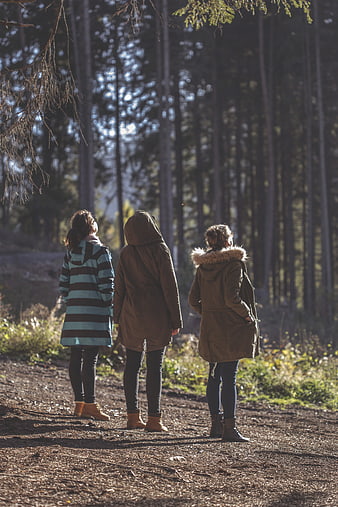 Three women standing on a forest path in winter coats