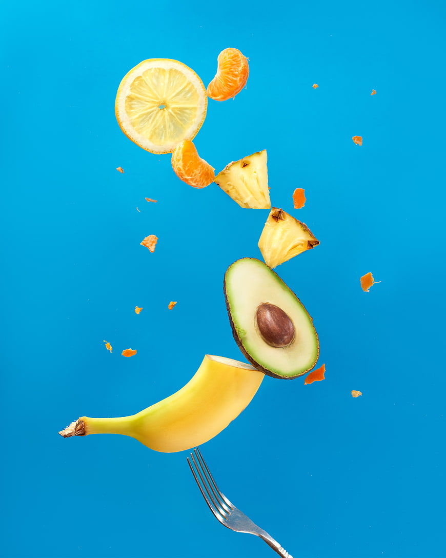 Floating Fresh Fruits and Avocado on Blue Background