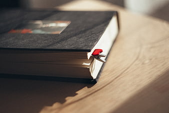 Close-up of black notebook with red heart bookmark on wooden table