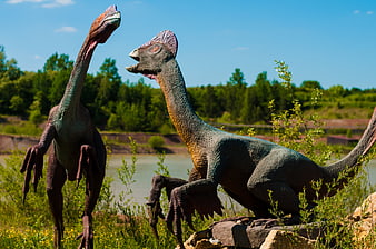 Two realistic dinosaur models in a natural park setting
