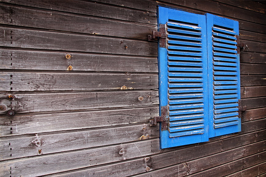 Blue wooden shutters on weathered rustic wall