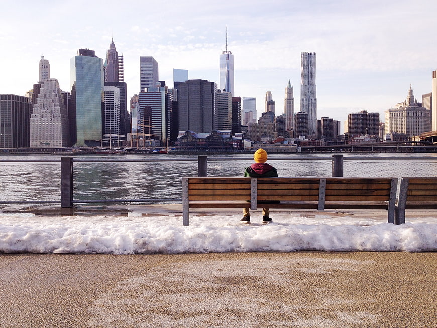 Child in Yellow Hat Sitting on Bench Viewing NYC Skyline