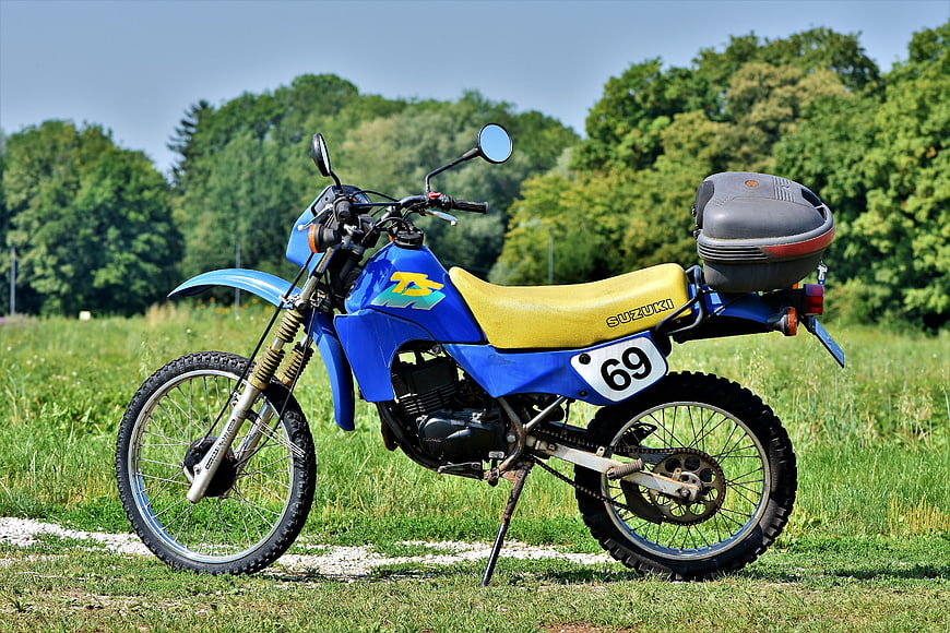 Blue Suzuki TS 50 Enduro Motorcycle Parked In Green Field