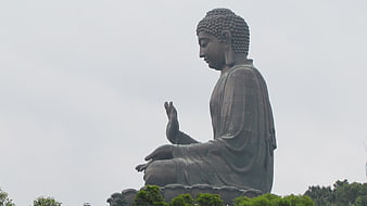Side view of large bronze Buddha statue against overcast sky