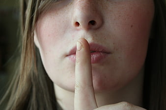 Close-up of woman holding finger to lips in silence gesture