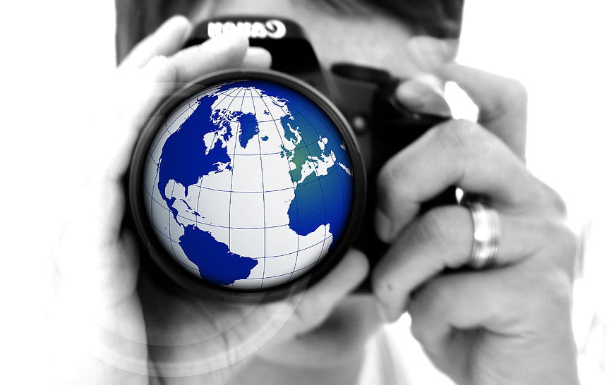 Photographer holding camera with globe lens concept