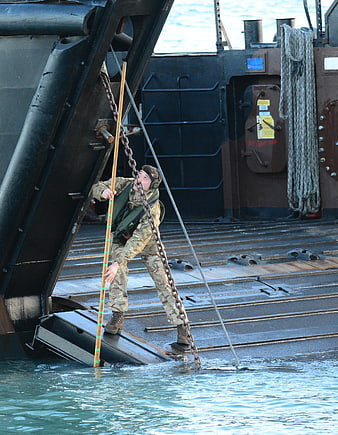 Soldier disembarking military landing craft into water