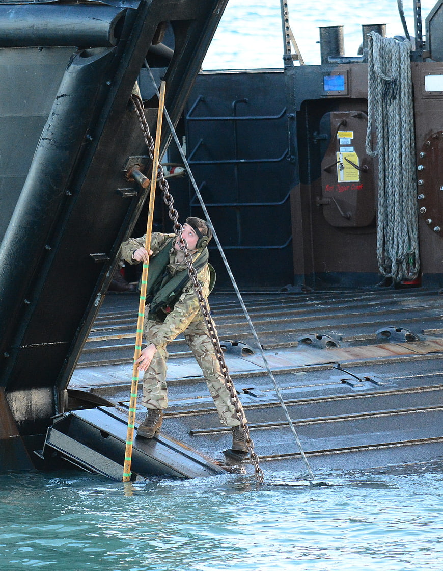 Soldier disembarking military landing craft into water
