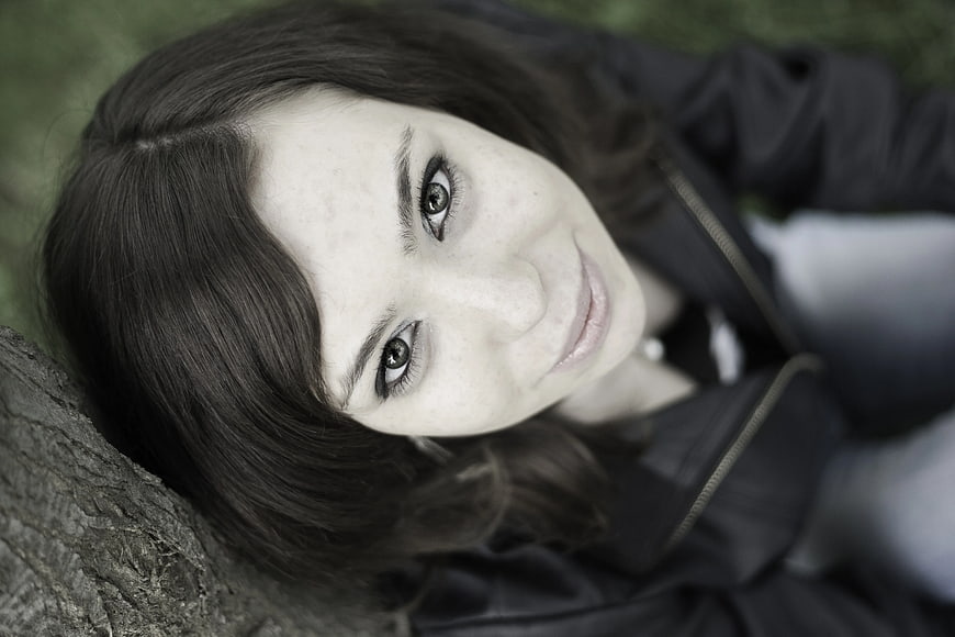 Close-up portrait of smiling woman lying on grass