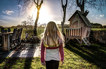 Girl with Blonde Hair Standing in Backyard Near Playhouse