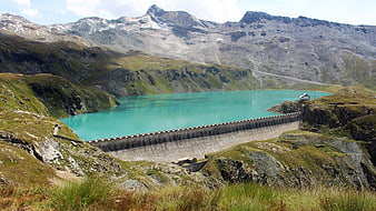 Turquoise Alpine Reservoir with Concrete Dam and Snowy Peaks