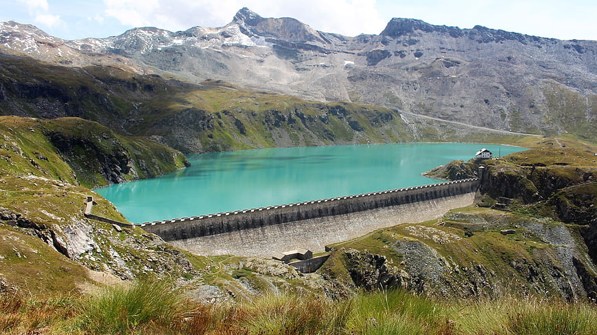 Turquoise Alpine Reservoir with Concrete Dam and Snowy Peaks