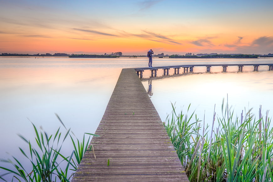 Lone photographer on wooden pier at sunset