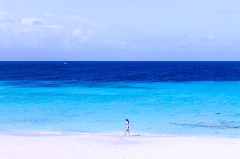 Woman Walking on White Sand Beach with Turquoise Ocean