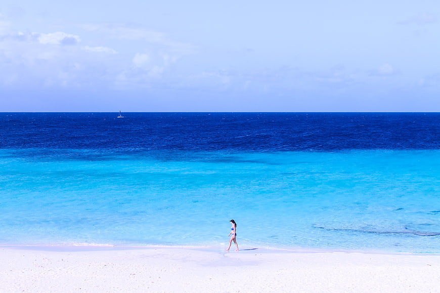 Woman Walking on White Sand Beach with Turquoise Ocean