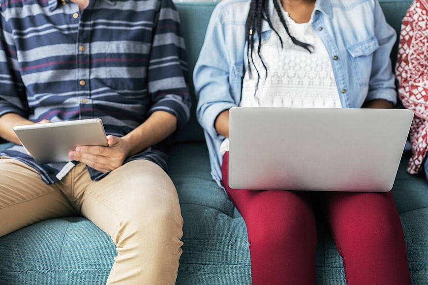 Couple Using Laptop and Tablet on Blue Sofa
