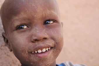 Close-up portrait of smiling African child with dust on face