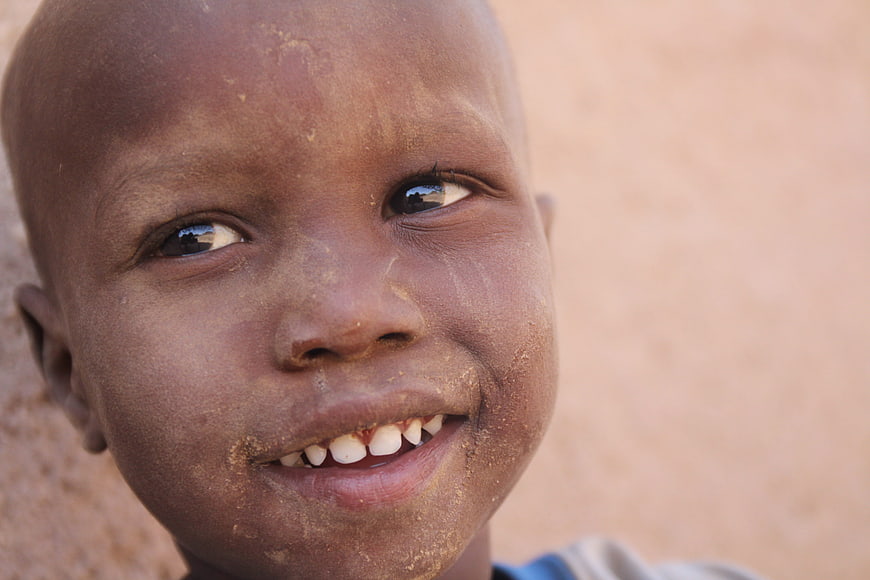 Close-up portrait of smiling African child with dust on face