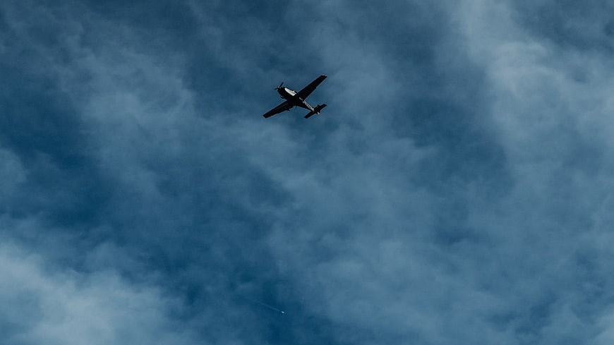 Vintage Propeller Airplane Flying Against Dramatic Blue Cloudy Sky