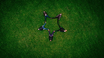 Aerial view of five friends forming a star shape on green grass