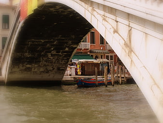 View under a stone bridge arch in Venice canal