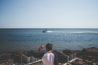 Man Gesturing at Speedboat on Ocean Horizon