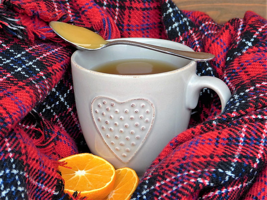 Warm tea with honey and orange on plaid scarf