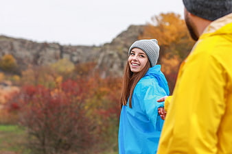 Happy couple hiking in autumn rain with colorful jackets
