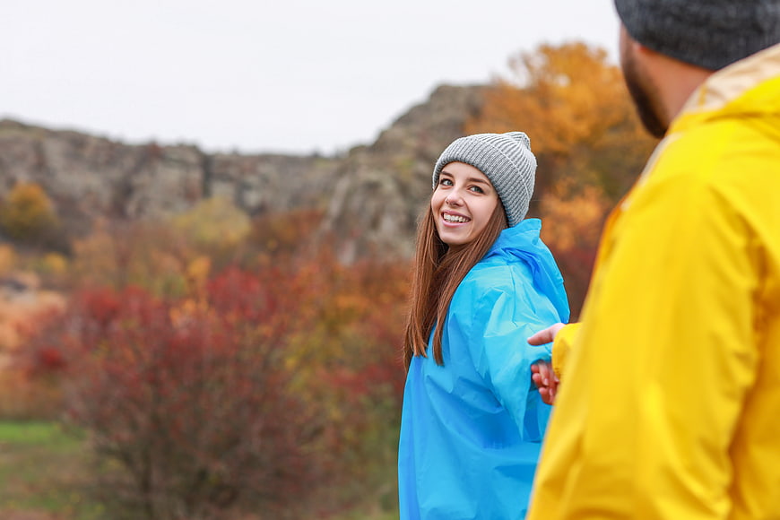Happy couple hiking in autumn rain with colorful jackets