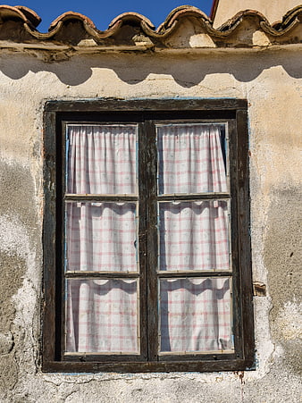 Traditional rustic window with checkered curtains on weathered wall
