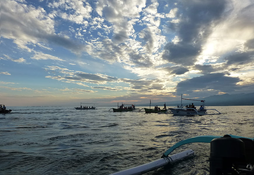 Traditional outrigger boats on ocean at sunrise with dramatic clouds