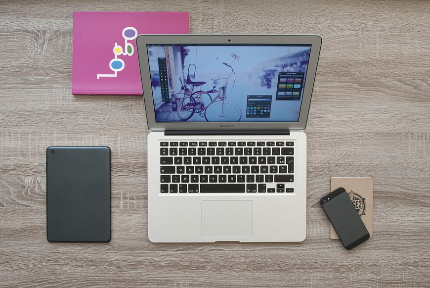 Flat lay workspace with laptop, tablet, smartphone, and notebook on wooden desk
