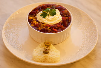 Chili con carne with sour cream and rice on a white plate