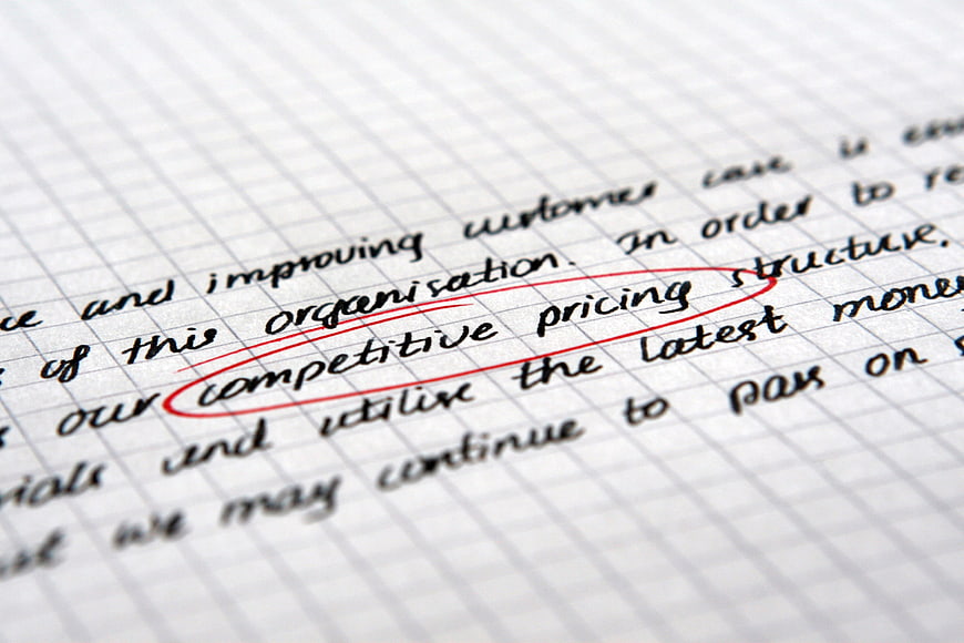 Close-up of handwritten competitive pricing text circled in red on grid paper