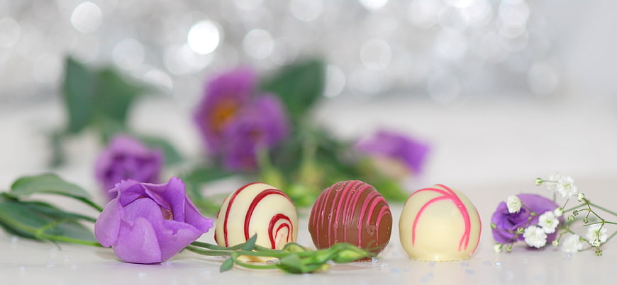 Decorated chocolate truffles with purple flowers and bokeh background