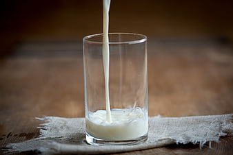 Fresh Milk Pouring into Glass on Wooden Table