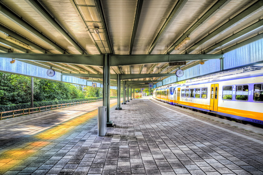 Empty train station platform with yellow and blue commuter train