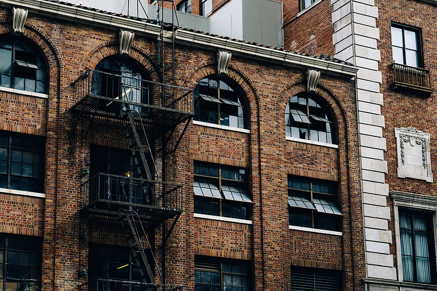 Urban brick building facade with fire escape and arched windows
